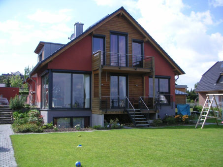 Wohnhaus mit rotem Giebel, Holzfassade und großer Verglasung zum Garten