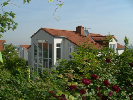 Wohnhaus mit Wintergarten hinter blühendem Garten