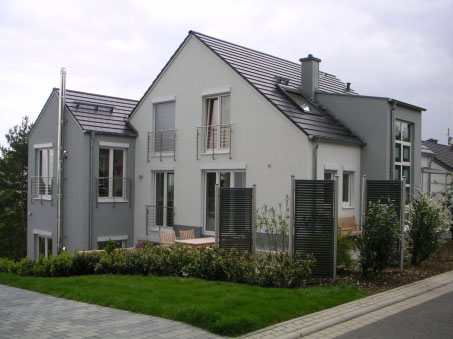 Graues Doppelhaus mit Satteldach und Vorgarten